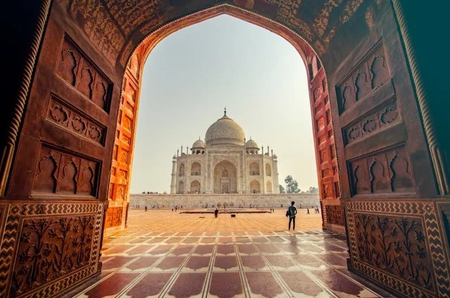 Taj Mahal in Agra viewed through a red sandstone arch