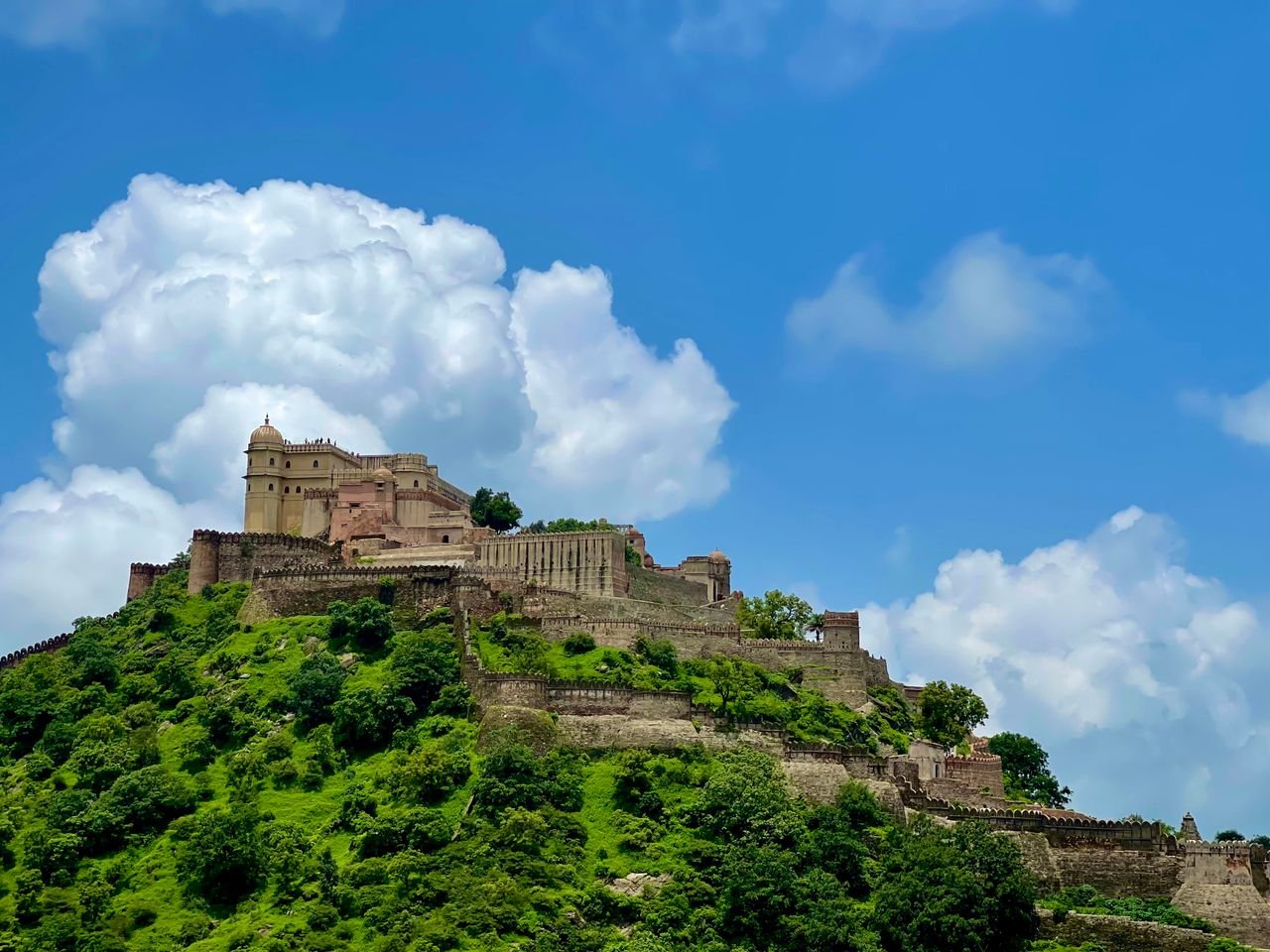Kumbhalgarh Fort on a green hill beneath a blue sky