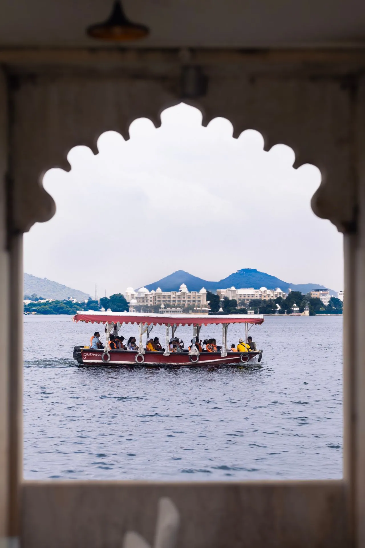 Passenger boat on Lake Pichola framed by an arched window