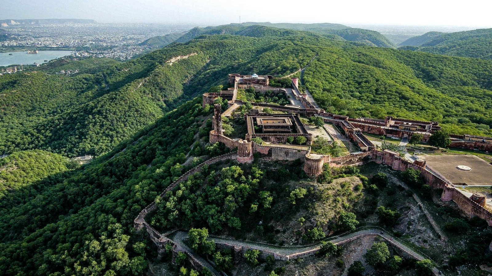 Aerial view of a hilltop fort surrounded by green hills near Jaipur