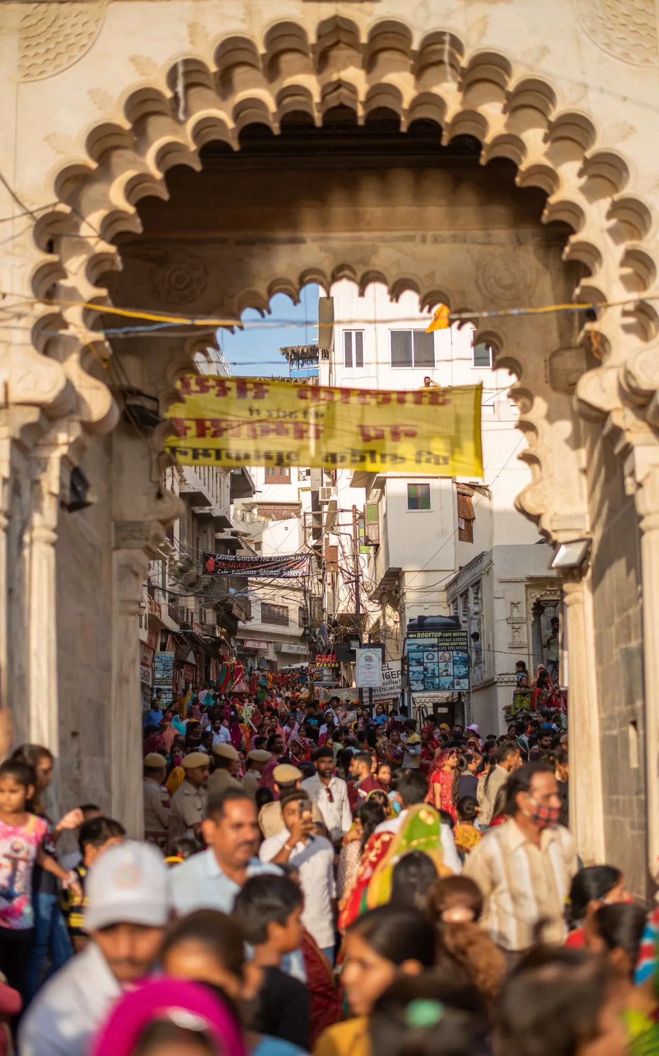 Crowded Udaipur old city street viewed through an ornate stone gateway