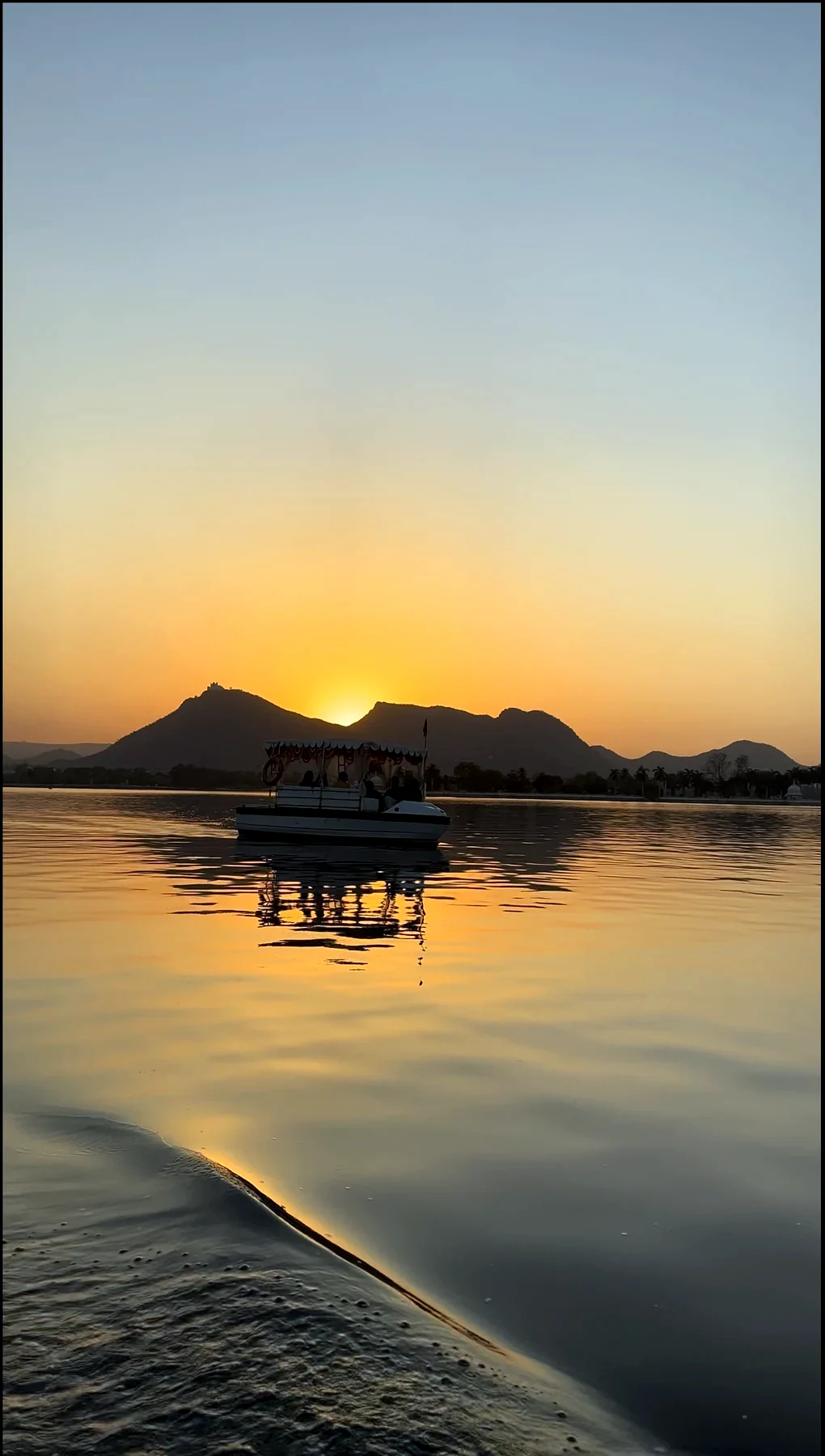 Passenger boat on Lake Pichola framed by a scalloped stone arch