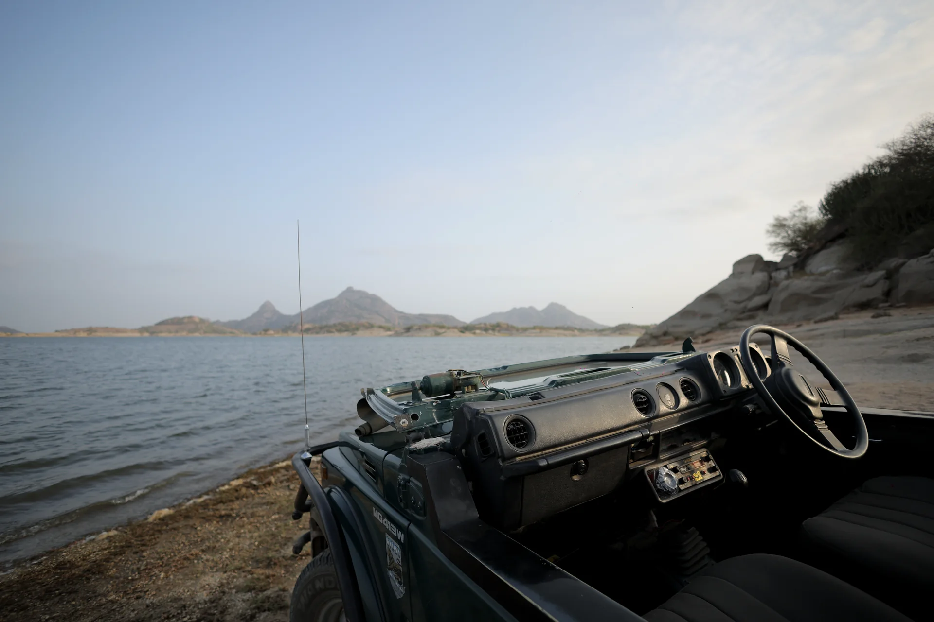 Jawai safari jeep parked beside the reservoir and granite rocks