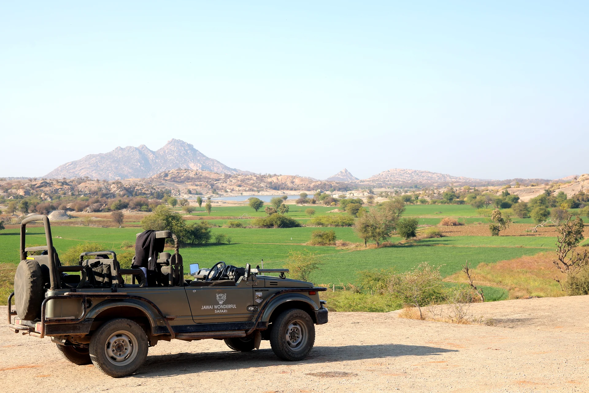 Open safari jeep overlooking Jawai’s farmland and granite hills