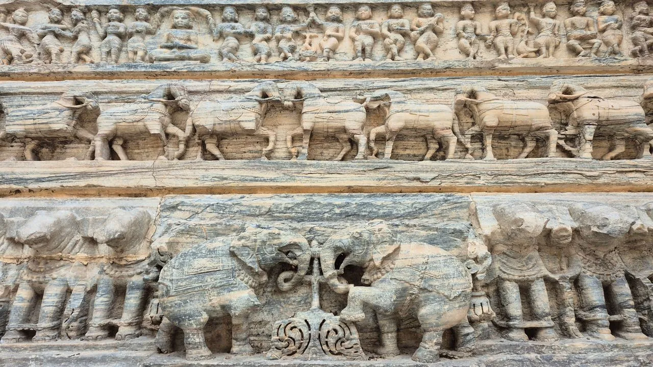 Rows of elephant reliefs and human figures carved into a stone temple wall