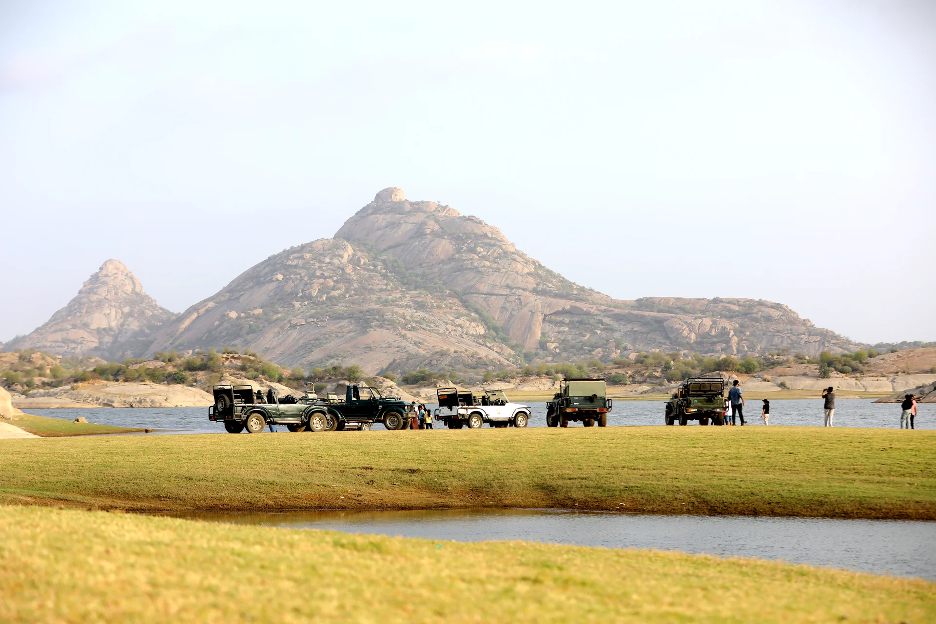 Safari jeeps beside Jawai Bandh with granite hills in the background